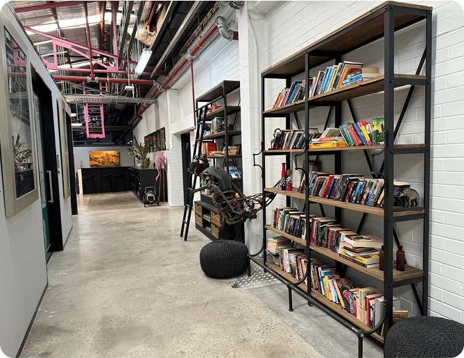 Modern office interior showcasing bookshelves filled with books, artistic decor, and vibrant workspace environment at Perceptiv Media in Kingsgrove, reflecting creativity and connectivity.