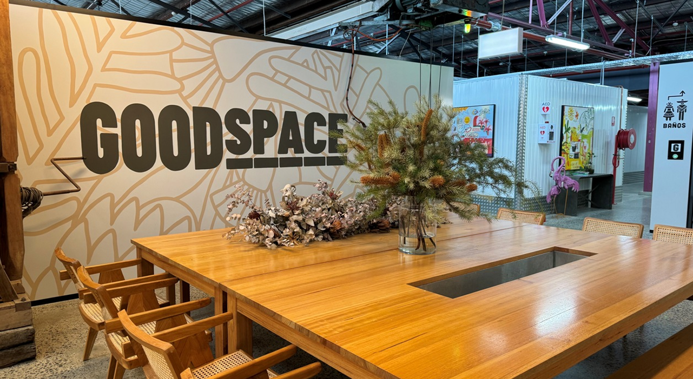 Modern meeting space with "GOODSPACE" mural, wooden table, and decorative plants, reflecting Perceptiv Media's creative and strategic environment for business growth.