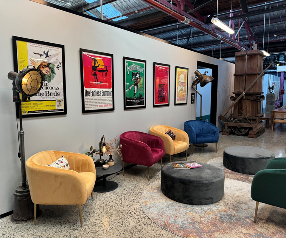 Colorful lounge area with modern chairs in yellow, blue, and red, surrounded by framed vintage movie posters, showcasing a creative workspace atmosphere for innovative marketing solutions.