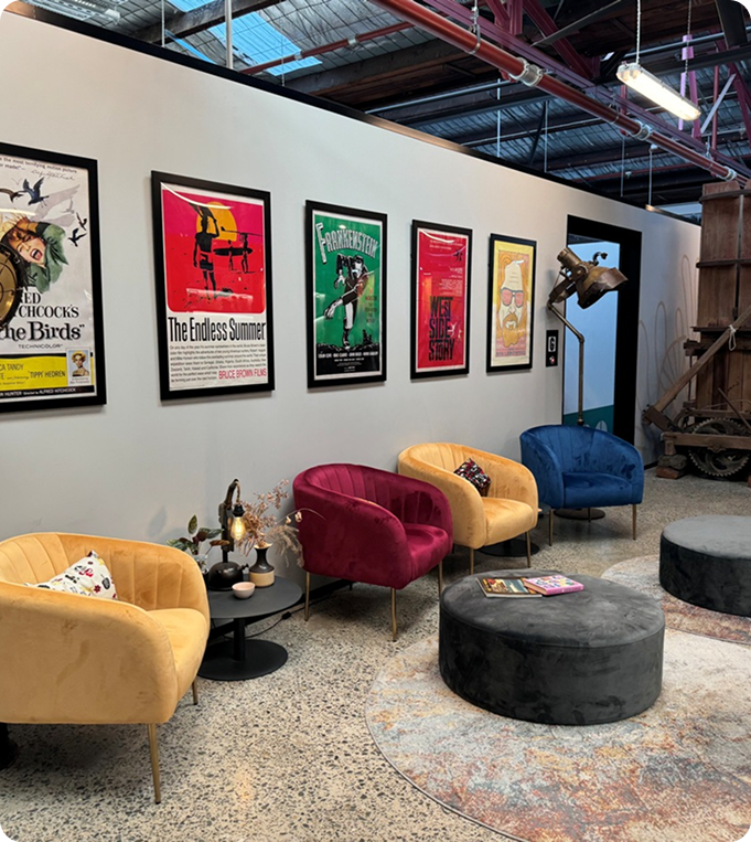 Colorful velvet chairs in a modern lounge area with vintage movie posters on the wall, showcasing a welcoming space for mechanics to discuss SEO strategies.