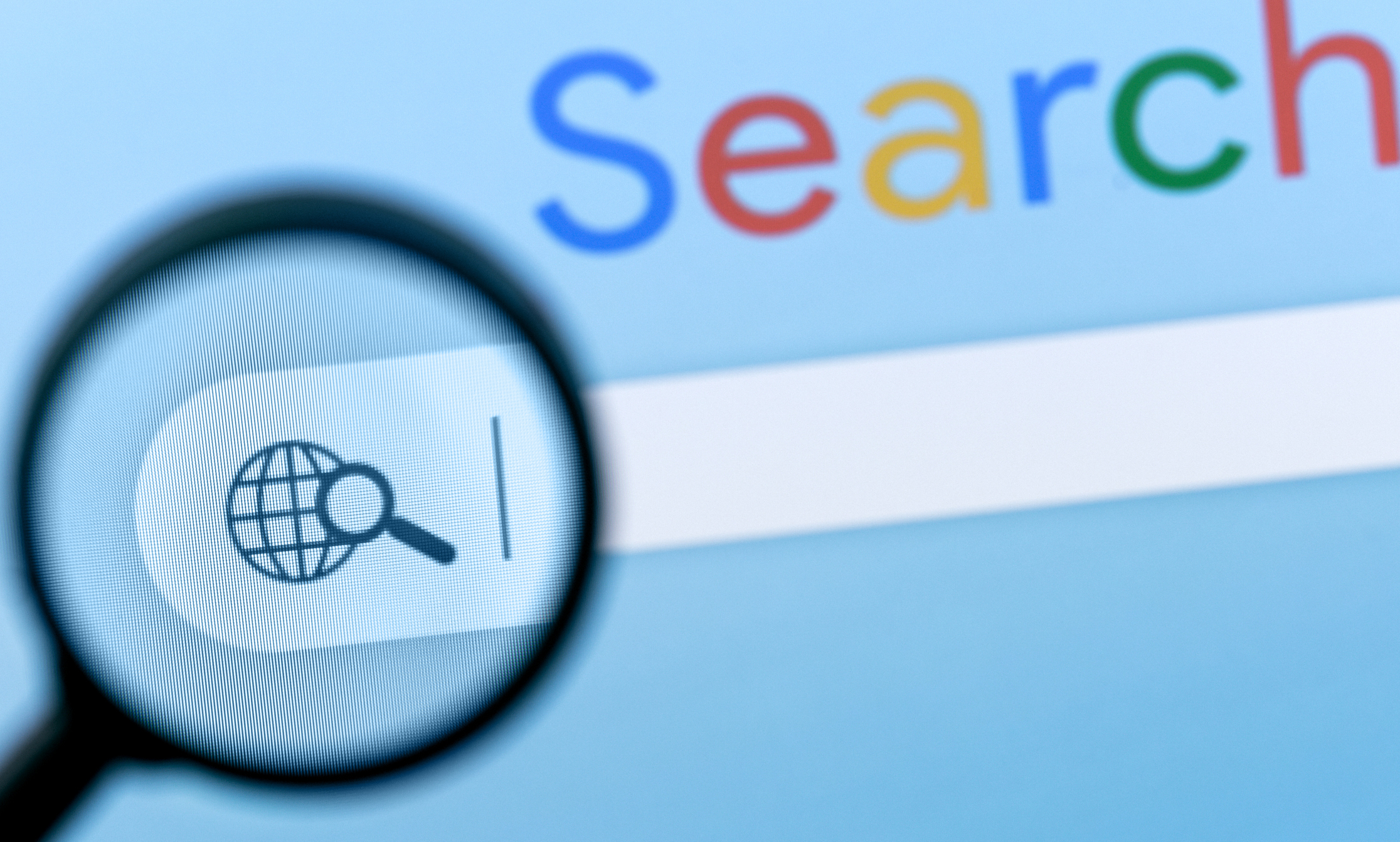 Magnifying glass focusing on a search icon with a globe, representing online search and SEO strategies for digital marketing.