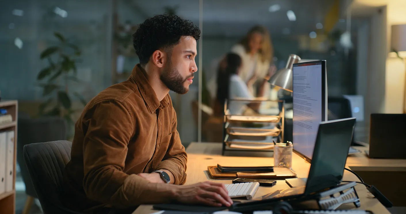 Man focused on computer screen in modern office environment, illustrating digital marketing and SEO audit processes.