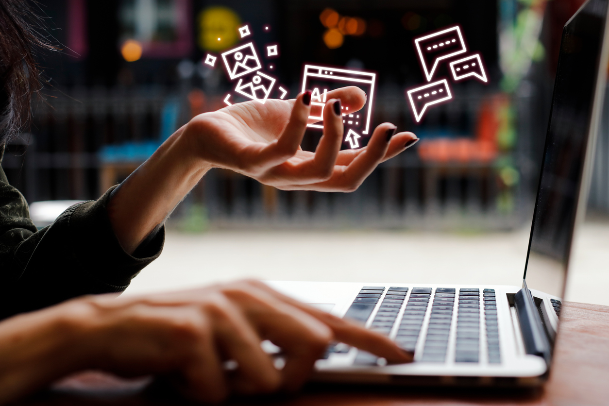 Person's hand gesturing towards digital icons representing AI, images, and chat bubbles above a laptop, illustrating AI SEO services in a modern digital marketing context.